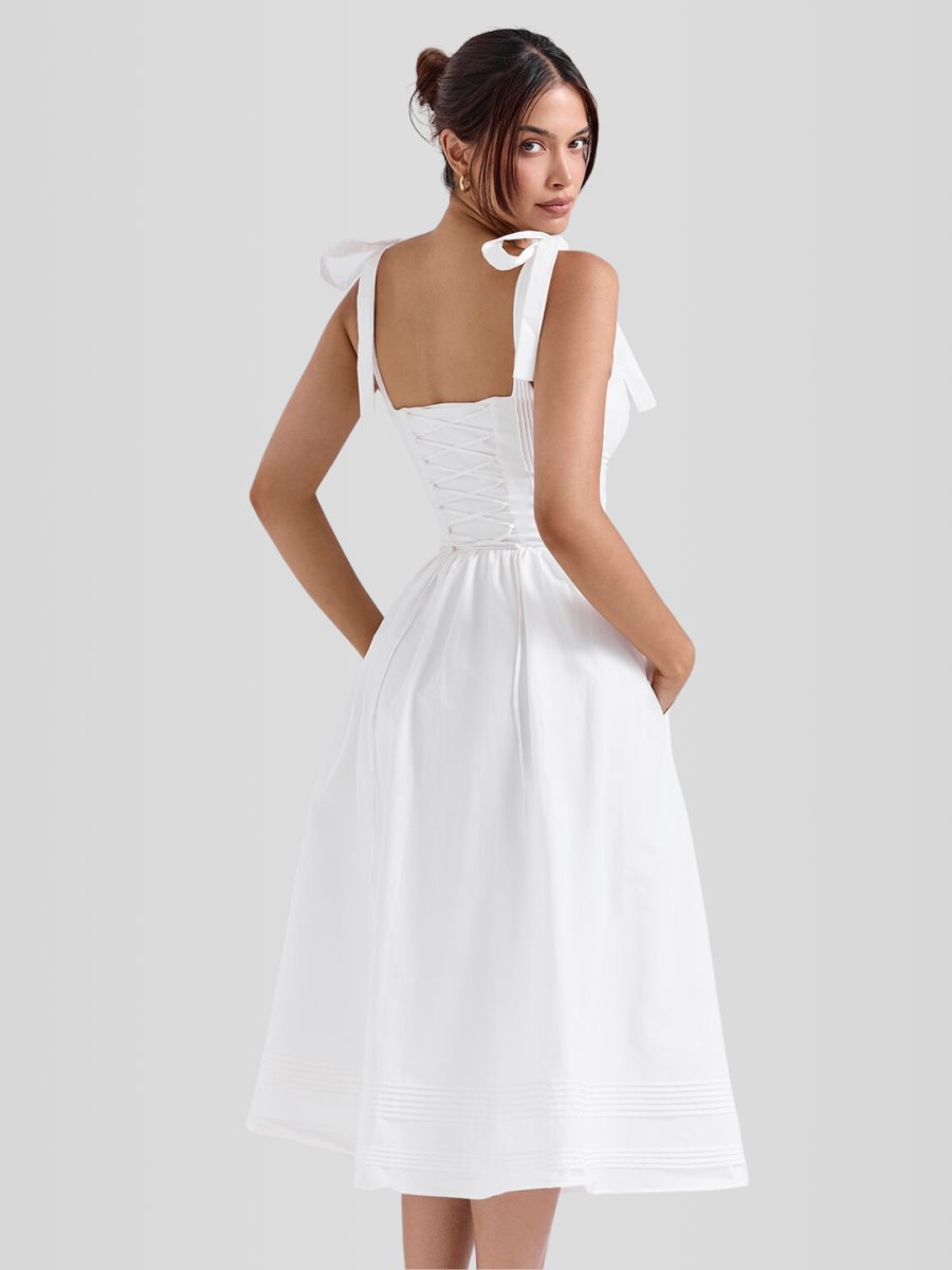 Modelo usando vestido midi blanco sin mangas con corset estructurado y ballenas internas. Diseño elegante con bolsillos discretos y ajuste entallado.