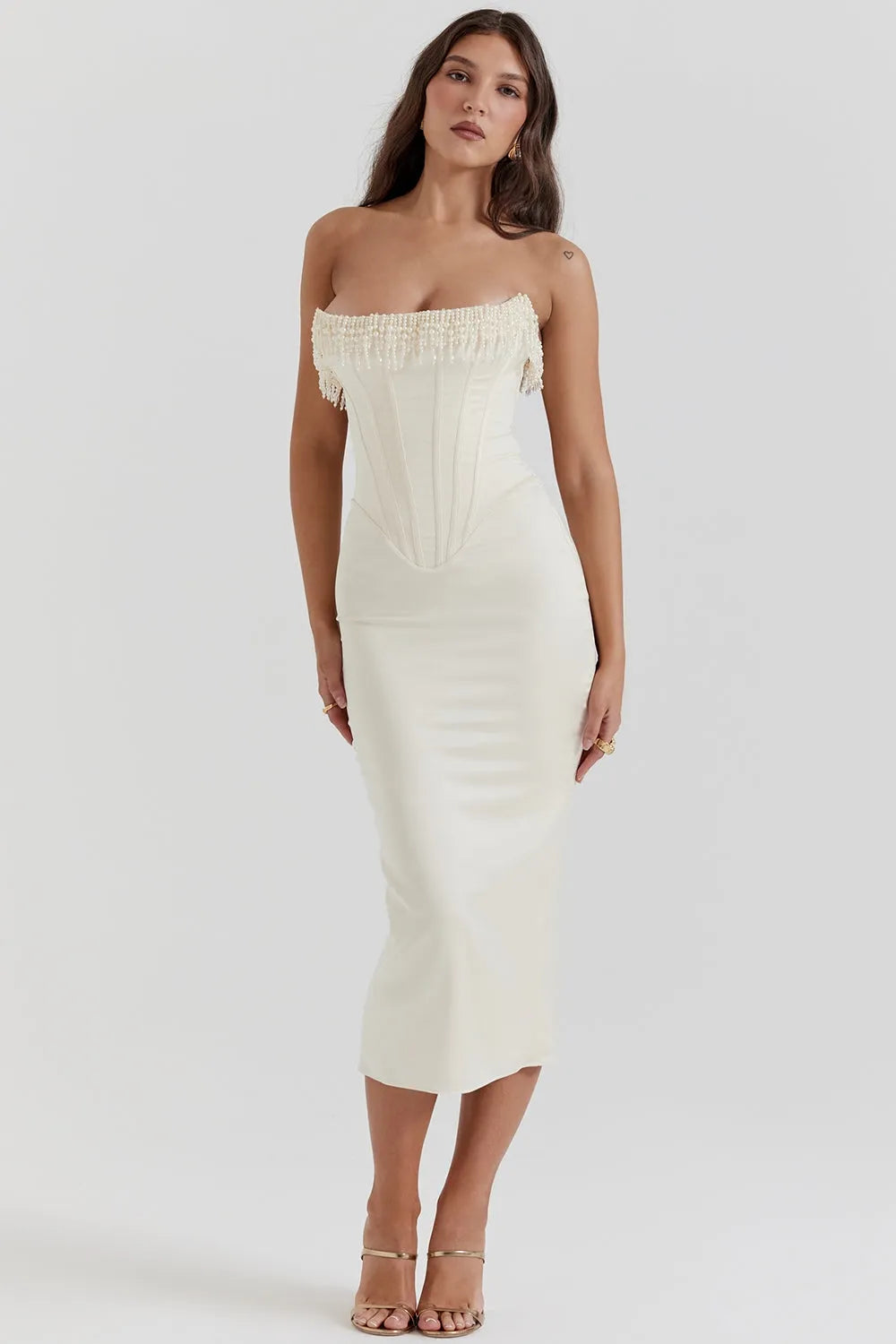 Modelo usando vestido midi blanco sin tirantes con detalle de perlas en el busto. Corte elegante ideal para boda civil o eventos formales.