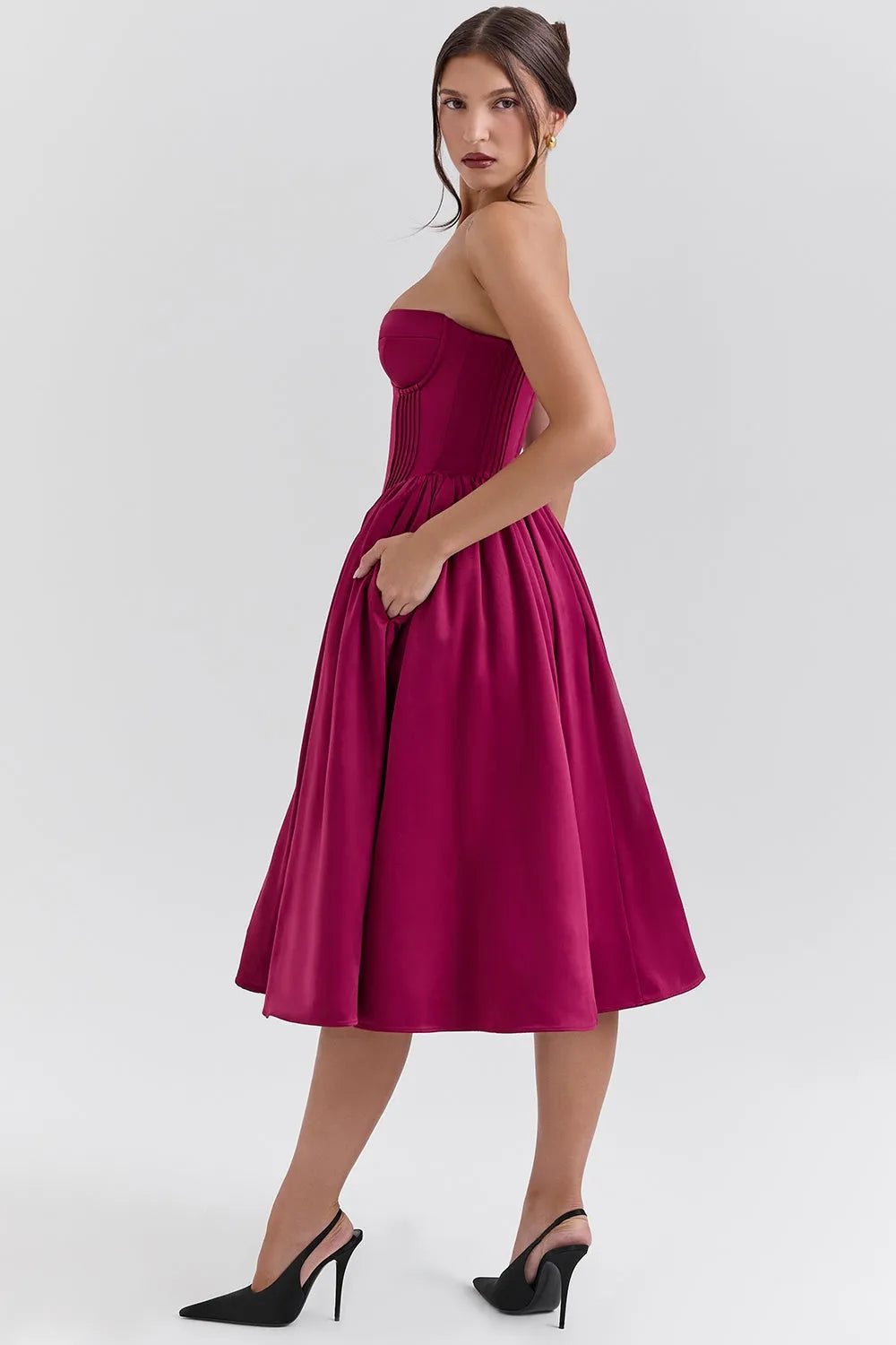 Modelo usando vestido midi juvenil color vino con corset estructurado y falda tipo bailarina. Ideal para fiestas, bodas o cenas elegantes.