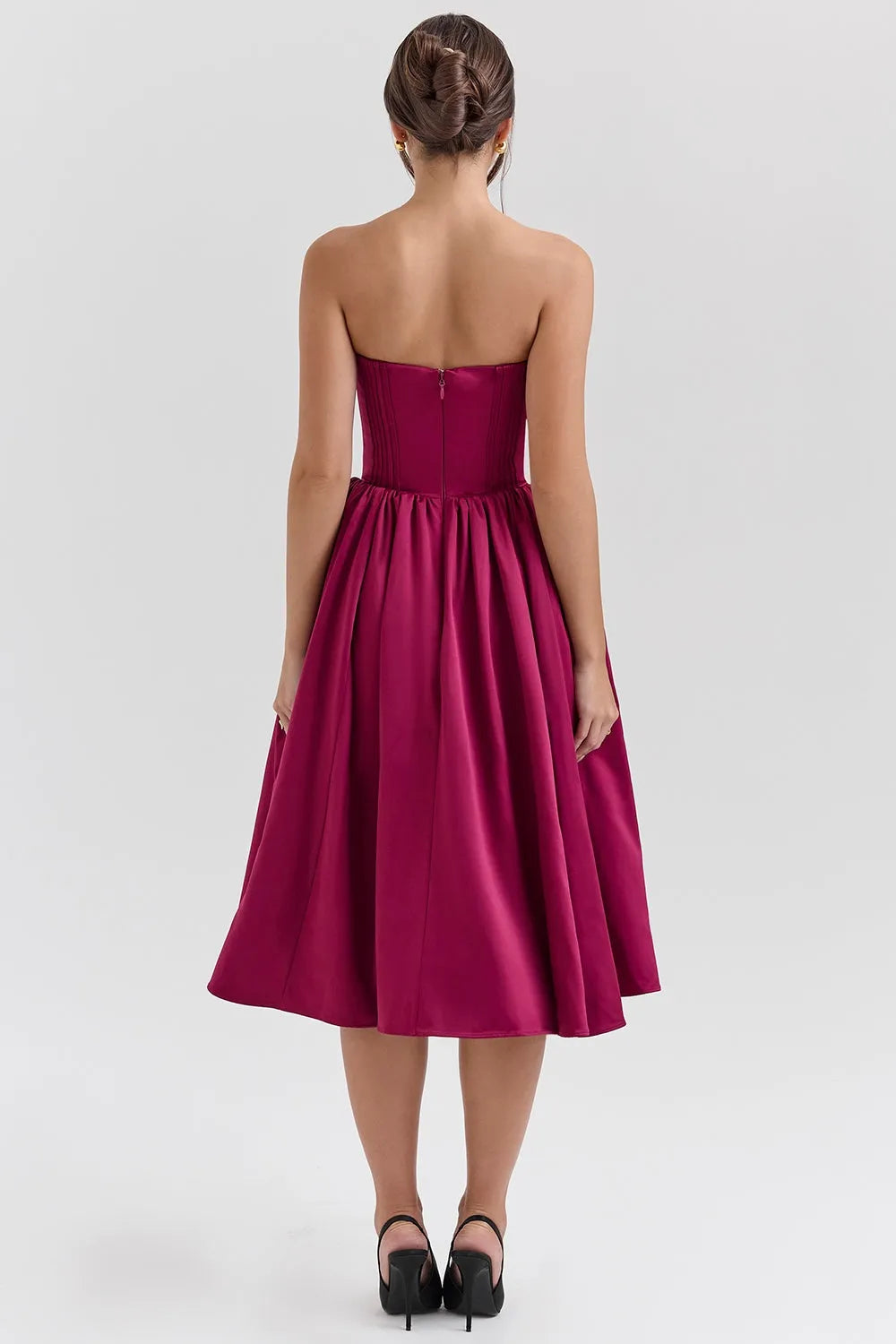 Modelo usando vestido midi juvenil color vino con corset estructurado y falda tipo bailarina. Ideal para fiestas, bodas o cenas elegantes.