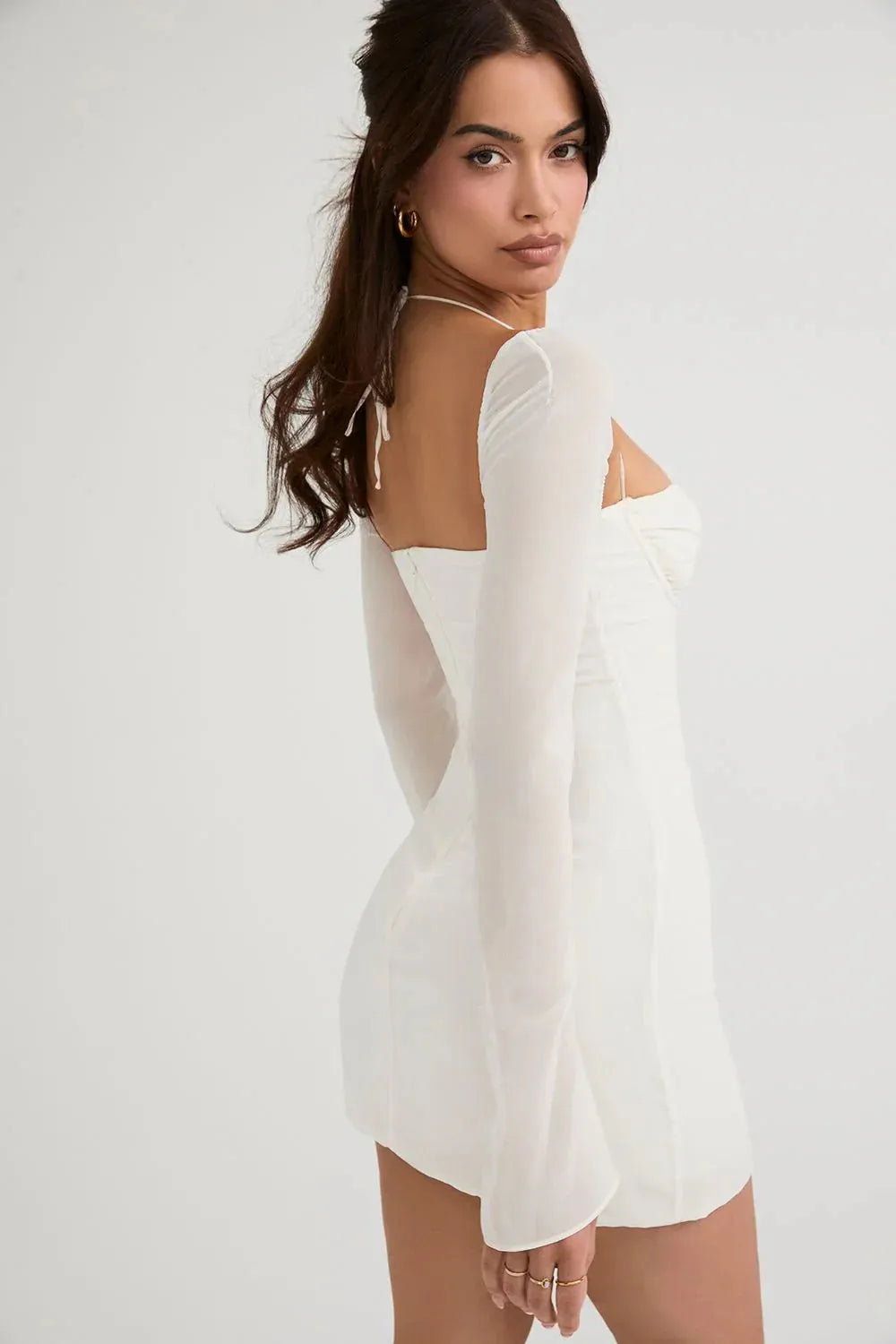 Modelo usando vestido blanco corto Mini Olivia con tirantes finos en jardín elegante