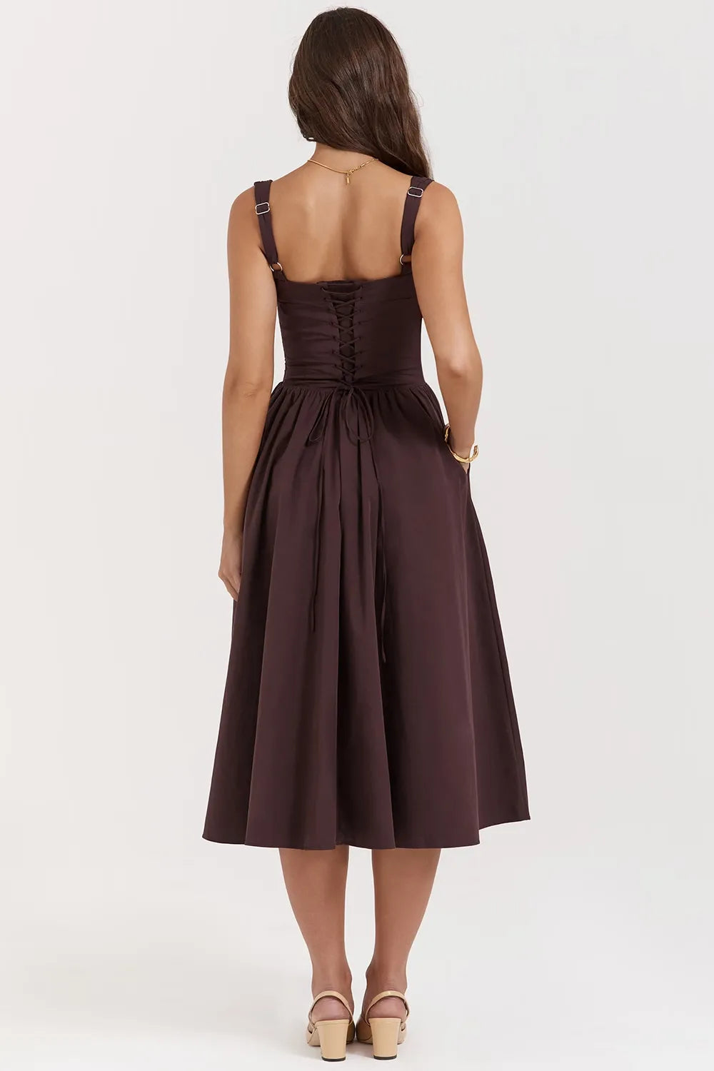 Modelo usando vestido midi color marrón con corset estructurado y falda con volumen.