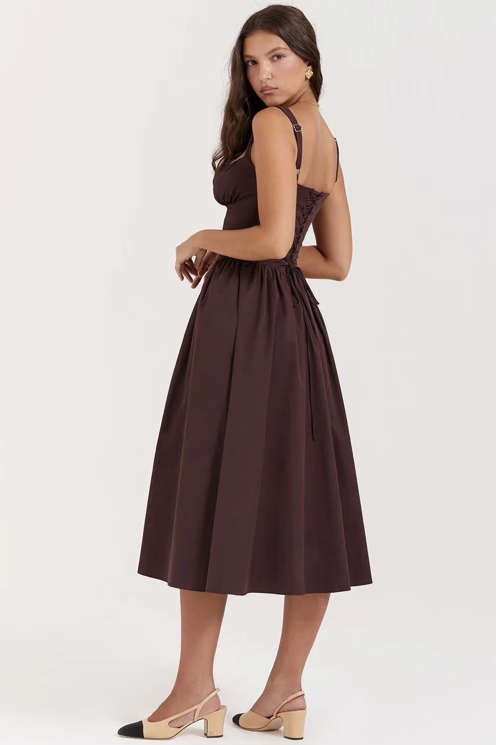 Modelo usando vestido midi color marrón con corset estructurado y falda con volumen.