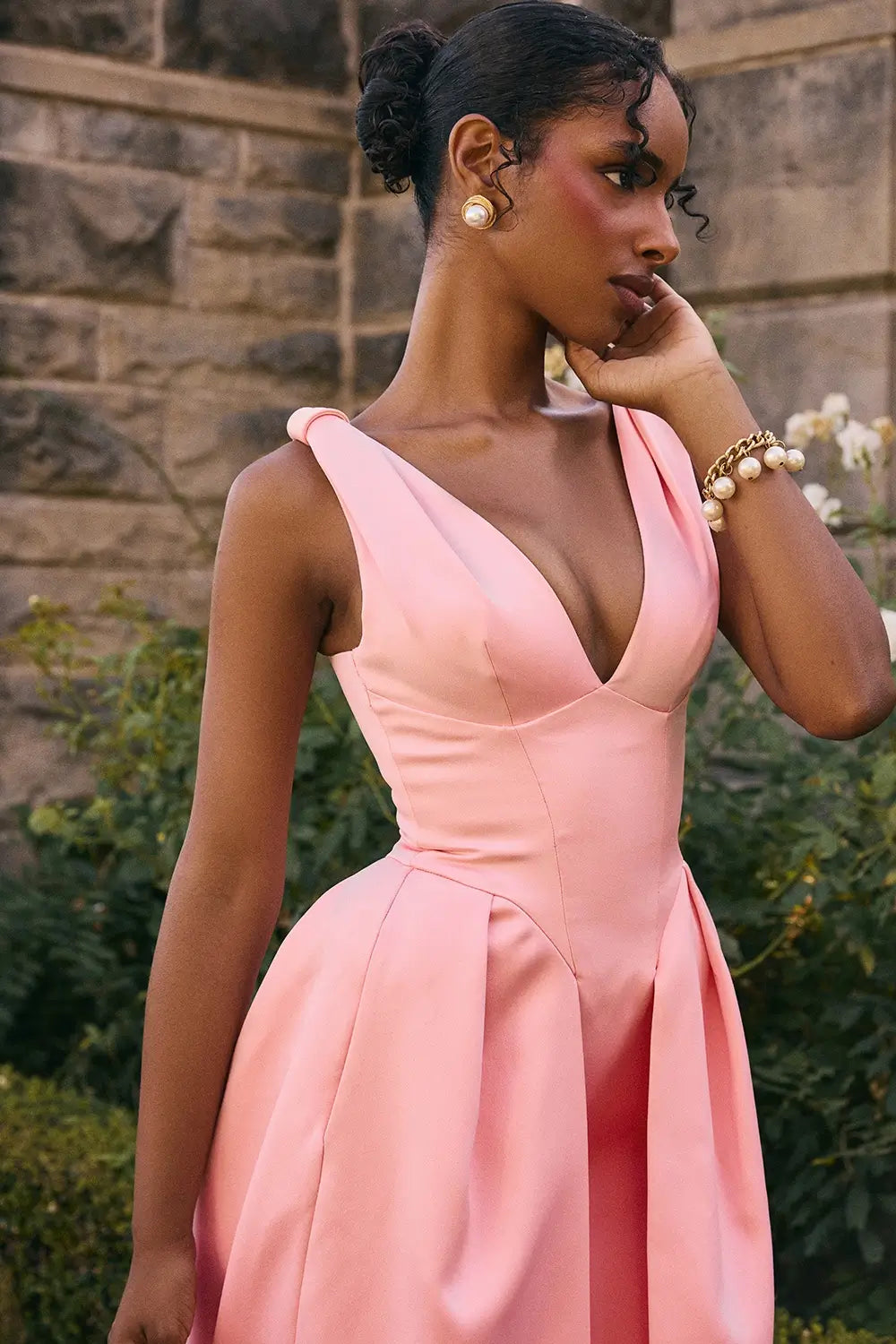 Modelo usando vestido midi rosa de satén plisado – diseño sofisticado con lazos y falda estructurada
