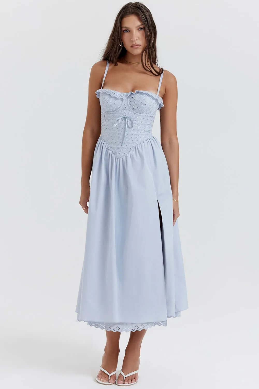 Modelo usando vestido midi azul cielo con bordado floral y tirantes finos. Diseño romántico y elegante ideal para eventos de primavera o verano.
