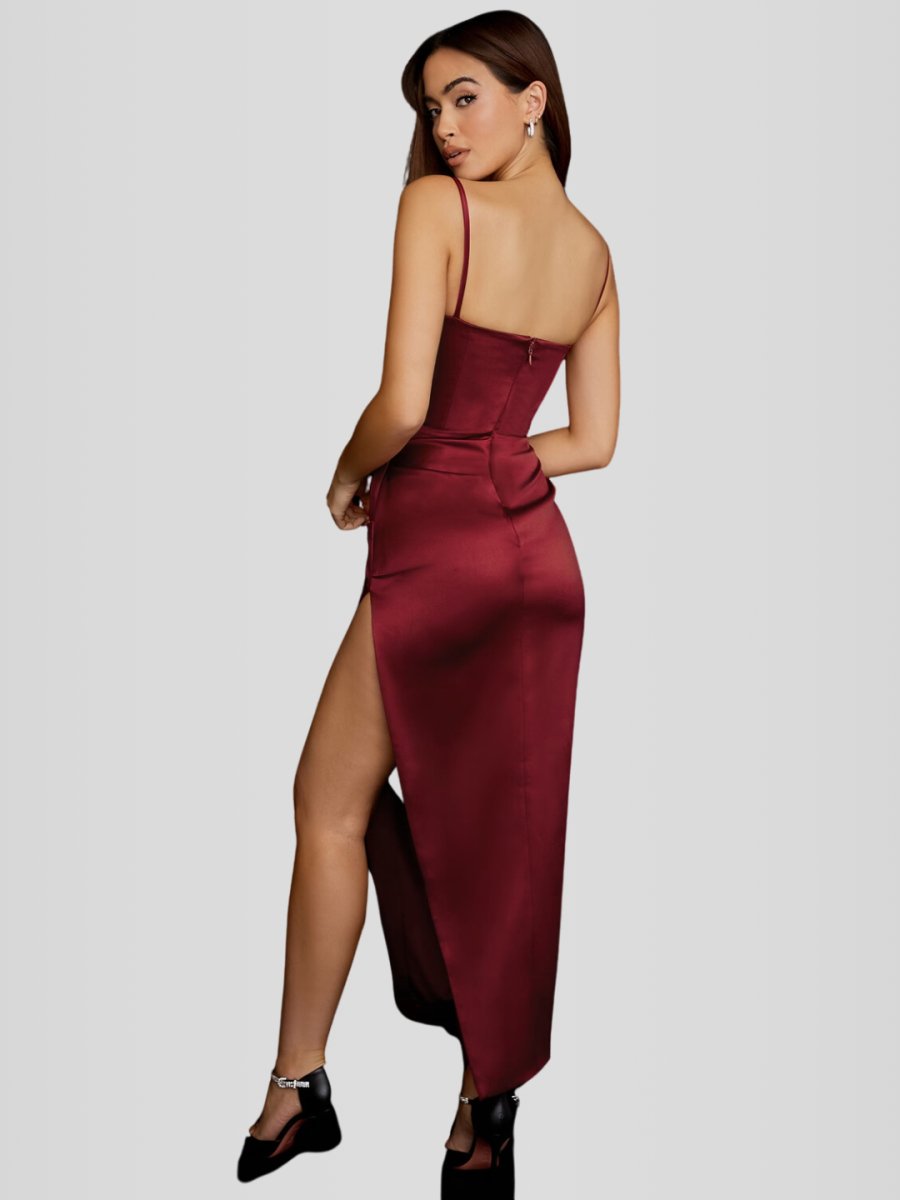 Modelo usando vestido largo color vino de satén con brillo sutil, corset con varillas y falda con abertura. Corte elegante que moldea la silueta.
