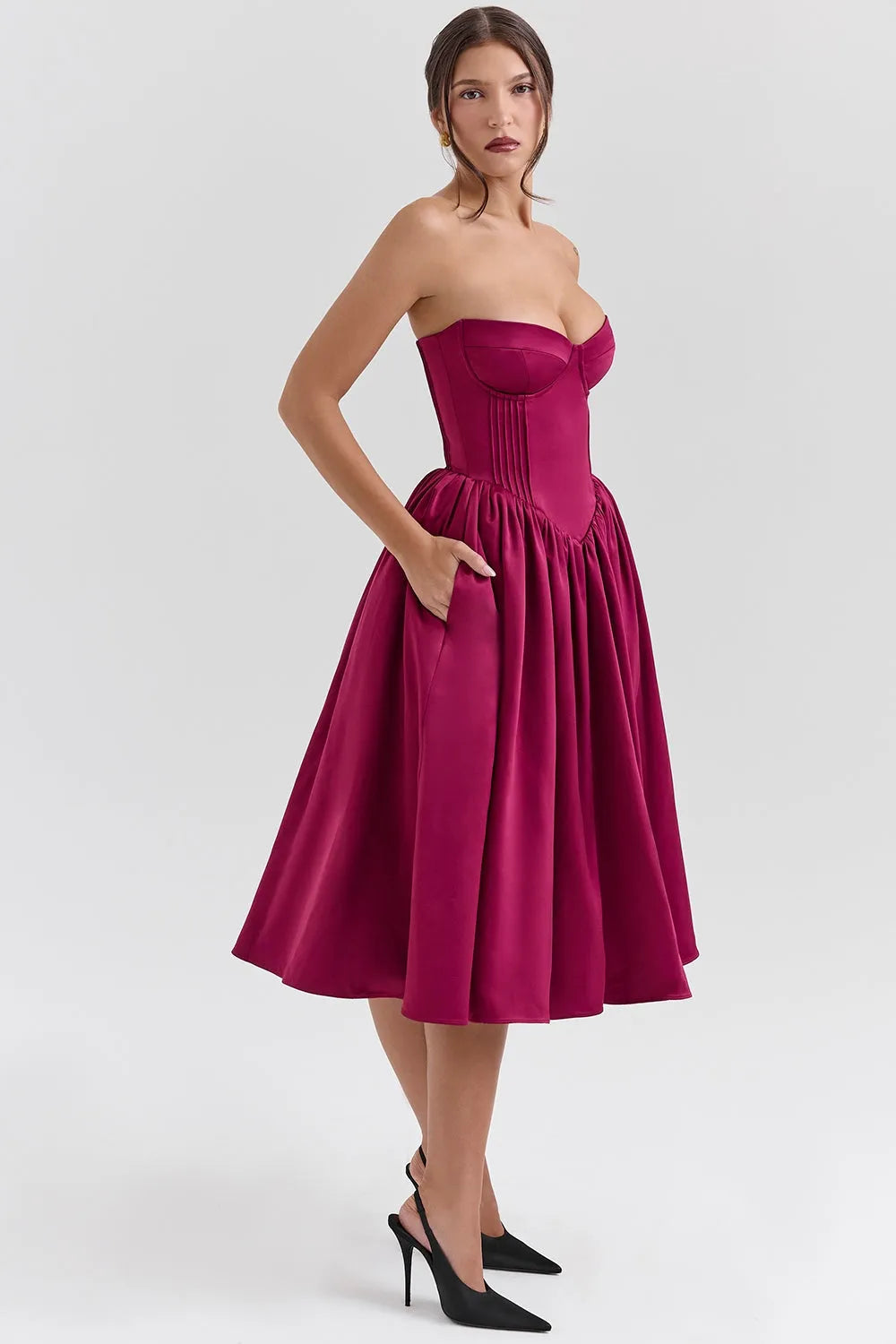 Modelo usando vestido midi juvenil color vino con corset estructurado y falda tipo bailarina. Ideal para fiestas, bodas o cenas elegantes.