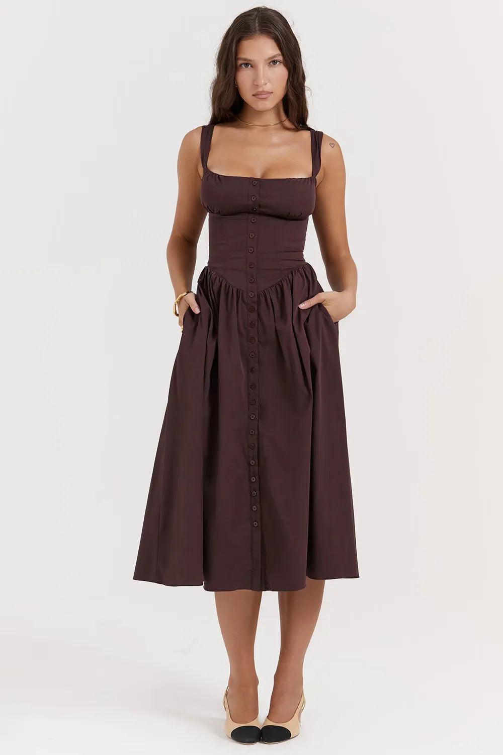 Modelo usando vestido midi color marrón con corset estructurado y falda con volumen.