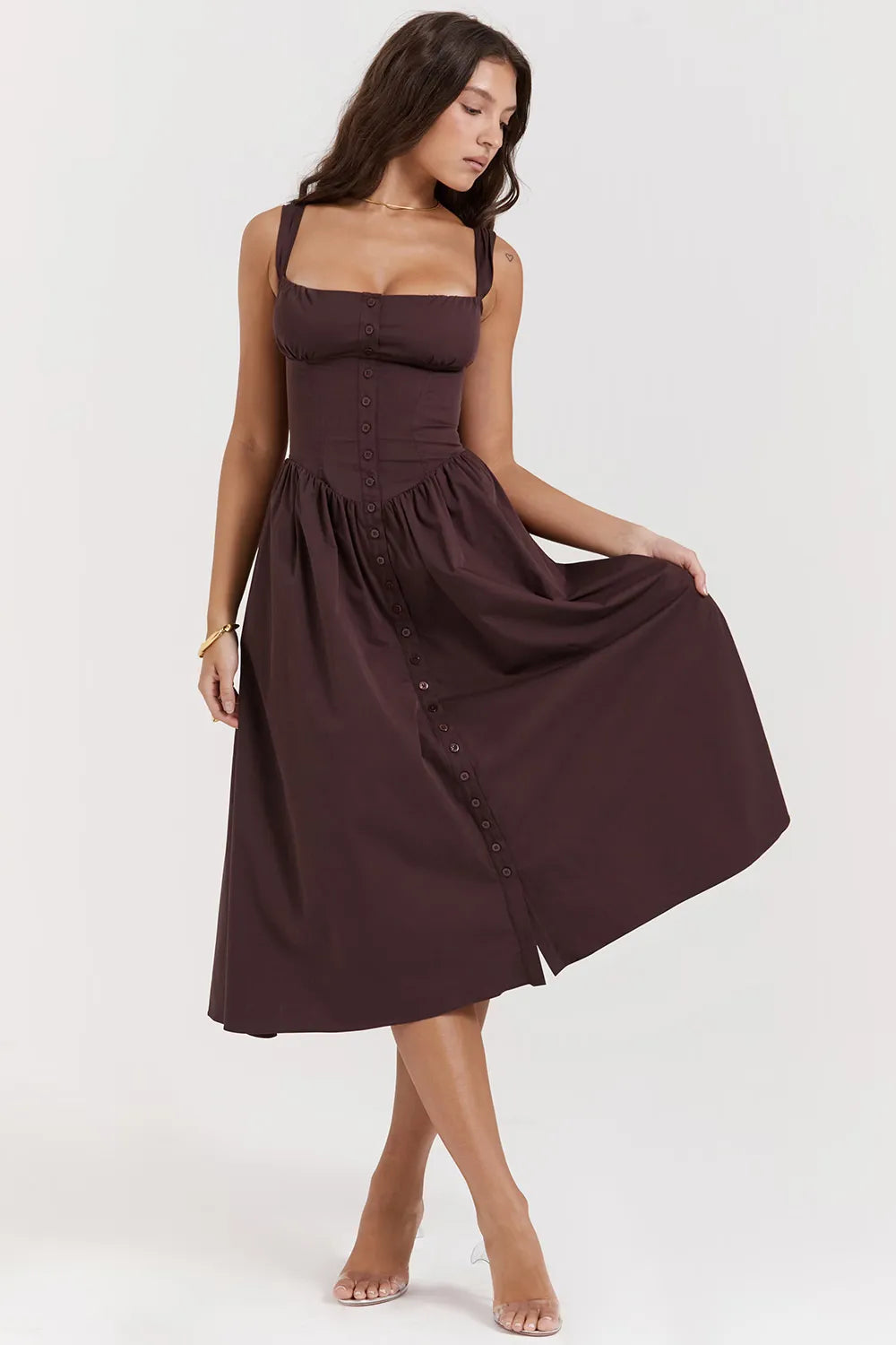 Modelo usando vestido midi color marrón con corset estructurado y falda con volumen.